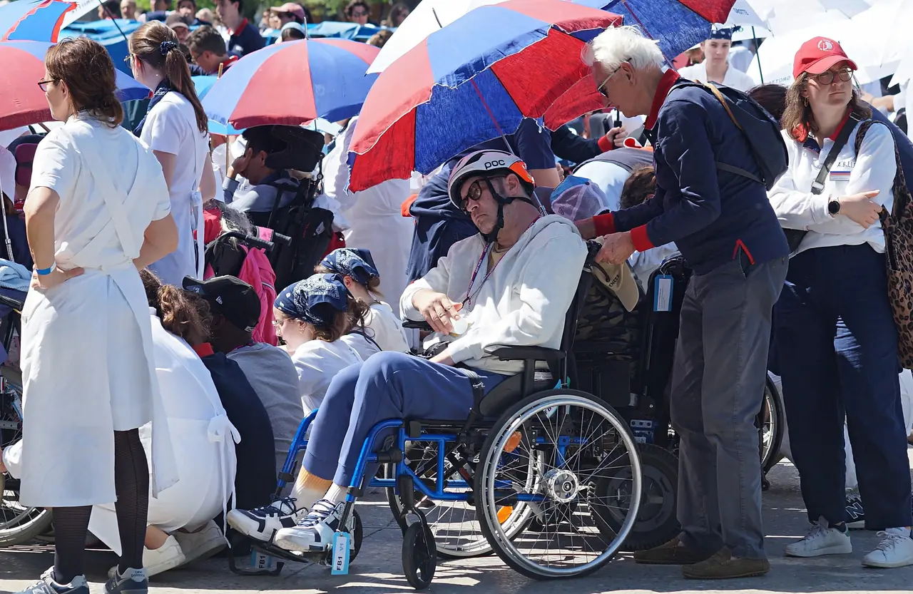 Des pèlerins et des hospitaliers de l’A.B.I.I.F. rassemblés sous les parasols pendant le pèlerinage